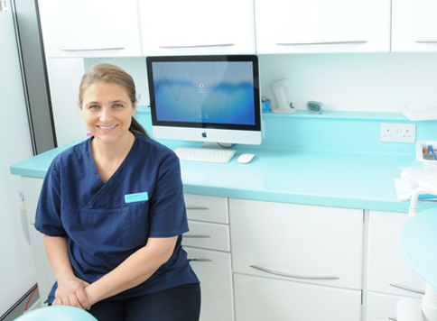 Dr Paula Brennan in her practice We Love Teeth, with a monitor on a cupboard behind her.